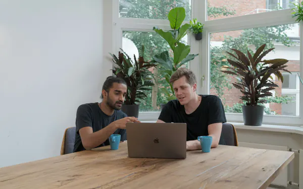 Two people working through a schedule on a laptop at a kitchen table